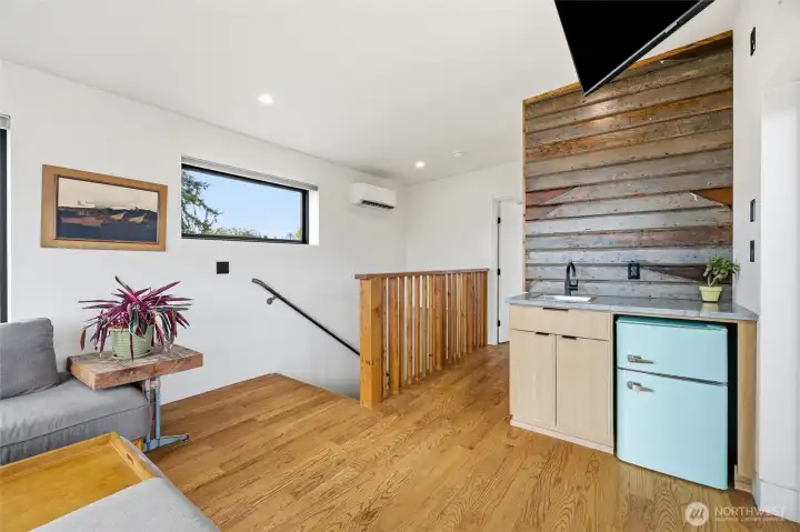 Family room includes a wet bar, beverage fridge, and ample windows.