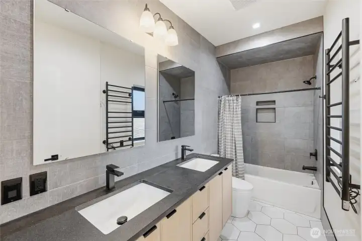 Third floor bathroom with tiled walls, tiled tub, dual sinks, quartz countertop, heated tile floors and heated towel bar.