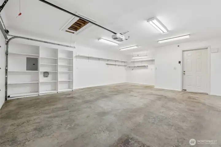 2 car garage with built in shelves and attic stairs for additional storage