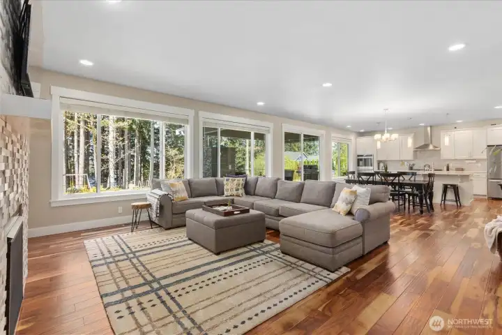 Open-concept living area with expansive windows bringing in natural light and surrounding greenery.