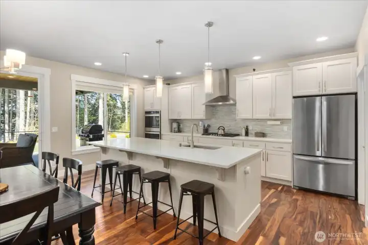 Spacious kitchen featuring a large island, quartz countertops, and white shaker cabinetry.