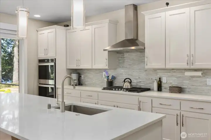 Stainless steel appliances, tile backsplash, and double oven enhance both style and function.