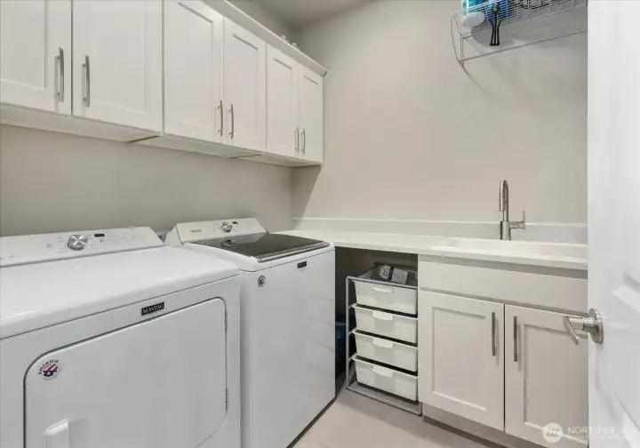 Dedicated laundry room with storage, counter space, and utility sink.