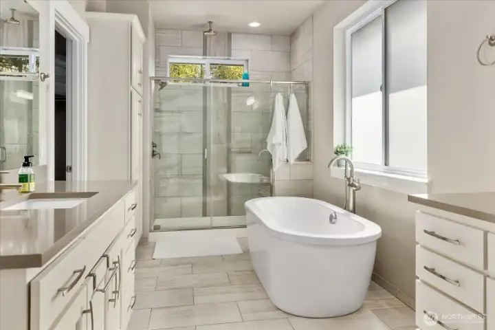 Spa-like bath featuring a freestanding soaking tub and glass-enclosed shower with tile surround.