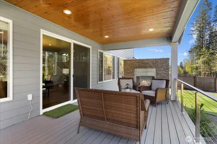 Covered outdoor living with wood-paneled ceiling, built-in fireplace, and space to relax year-round.