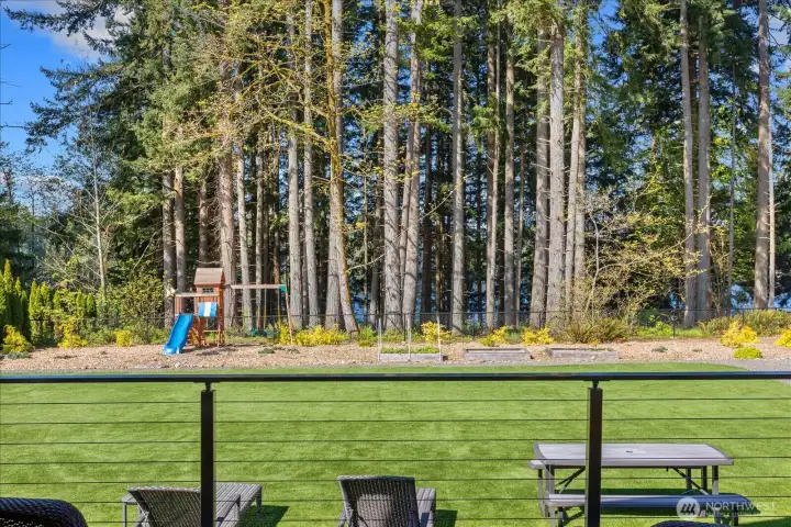 Cable railing frames a peekaboo lake view through the trees, creating a peaceful, natural backdrop to the backyard.