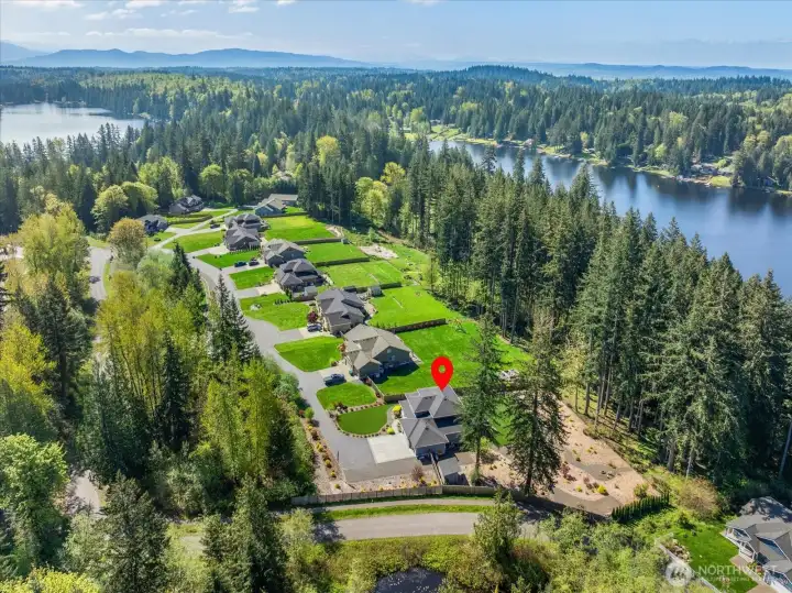 Aerial view showcasing the home’s setting, generous lot, and proximity to the lake.