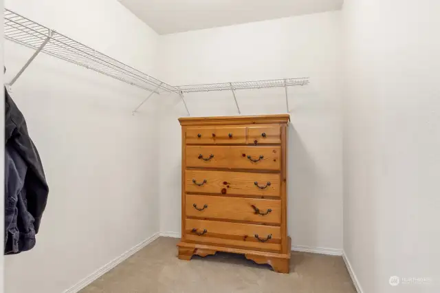 Practicality meets comfort in this walk-in closet. Carpeted floors, a wire shelf, and hanging bar keep things organized, while the extra space for a dresser means you can stow it all without feeling cramped.