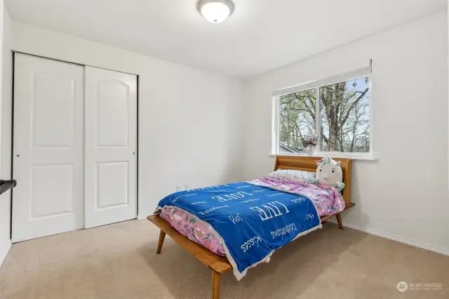 Oak trees peeking through the window, tan carpeting underfoot, and a closet with two-panel doors—this bedroom gives you all the calm vibes. The white walls and ceiling? They make the space feel bright and open, no matter the season.