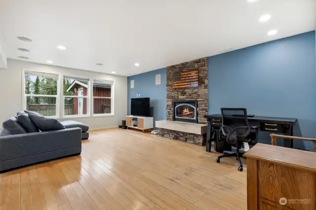 This family room has it all: bamboo floors, a statement-making stacked stone fireplace, and that perfect blue accent wall that connects the spaces. With recessed lighting and three windows framing the backyard, it’s the ideal mix of comfort and style.