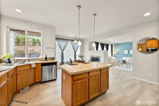 The center island provides extra storage space and a complementing tiled countertop highlighted by pendant lighting.