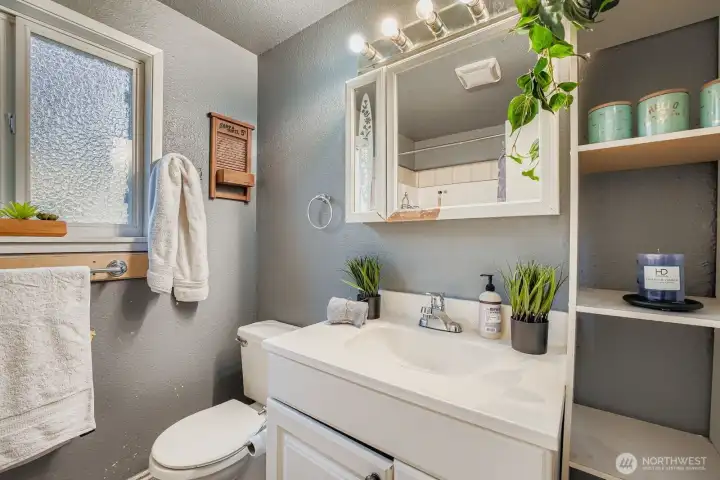 Full bathroom on second floor offers privacy window, tile flooring, plastic surround tub & shower, useful cubby shelves, medicine cabinet and vanity