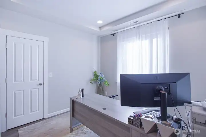 Bright and refined home office with tray ceiling detail and soft natural light—offering a focused, professional setting for remote work or study.