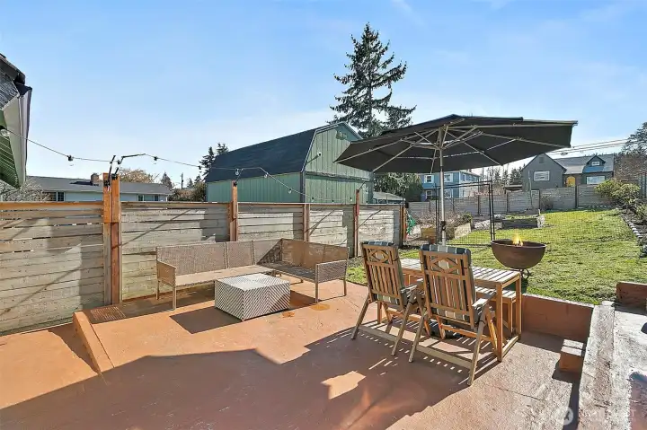 Patio off the family room overlooking fenced yard and garden beds. Gate to driveway off Winnifred. Large shed/outbuilding on the other side of fencing in driveway.