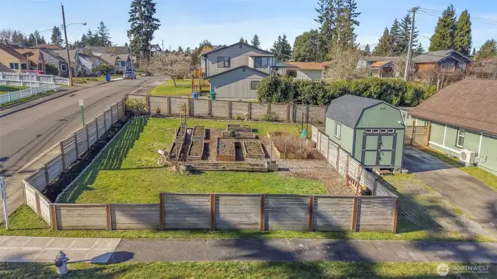 Corner lot, with a fully-fenced yard featuring raised garden beds for a harvest of your desire. Landscaping in the garden beds around the interior of fencing. Neighborhood sidewalks and fire hydrant at the corner for extra sense of safety.