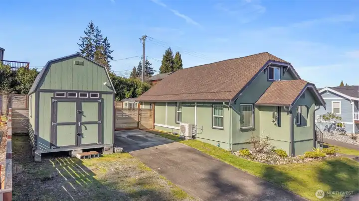 Paved driveway with large storage shed to the side of driveway. Front exterior of house from corner angle.