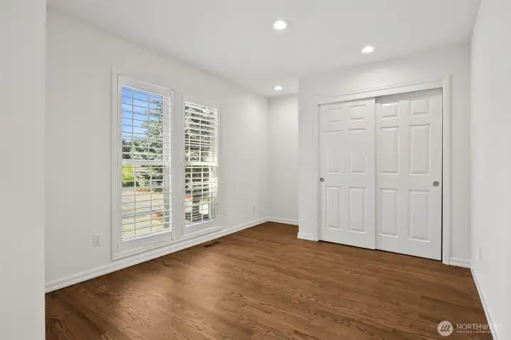 Bedroom #2 is located on the main floor- could be used as a home office space and offers custom shutters, floor to ceiling windows and oak flooring .