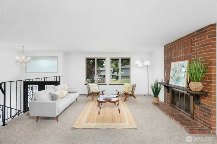 Main level living room with a floor-to-ceiling brick fireplace, two large windows that overlook the front yard.