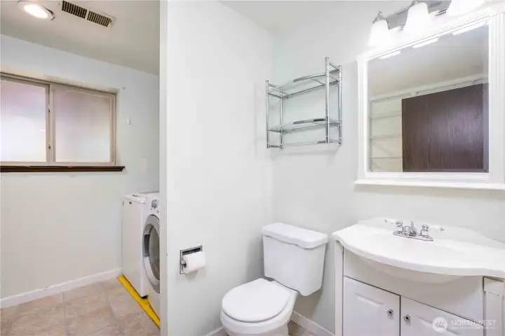 Downstairs half bathroom and utility room with wall mounted wire shelving along entire left wall and above washer and dryer.