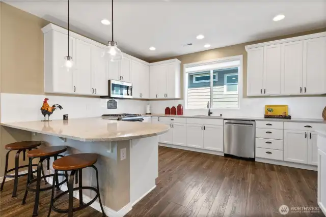 Bright kitchen with eat-in space and lovely rounded peninsula of upgraded quartz.