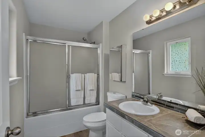 Relax and unwind in the private ensuite featuring a full tub with enclosure, spacious vanity, and modern finishes — a serene retreat within the primary suite.