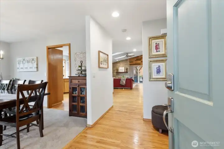 Bright and welcoming entryway with hardwood floors leading into the main living areas. The open sightline reveals a cozy living room, dining space, and natural light pouring in from large windows. Thoughtful décor and warm finishes create an inviting first step inside.