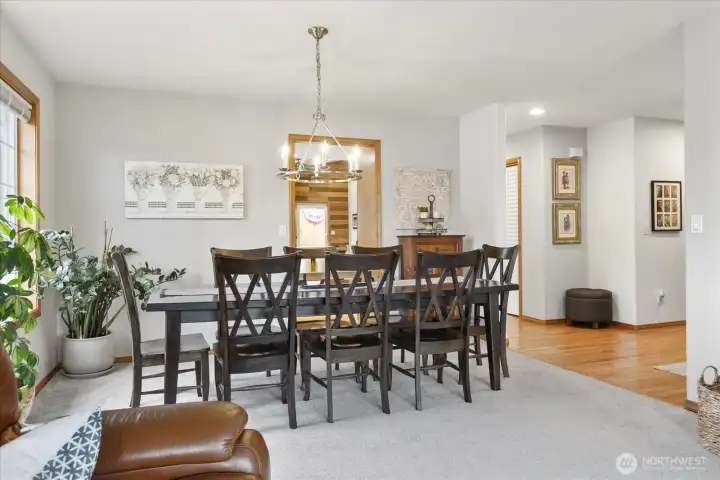 Formal dining room with space for full size table, modern chandelier, and large window overlooking the landscaped yard.
