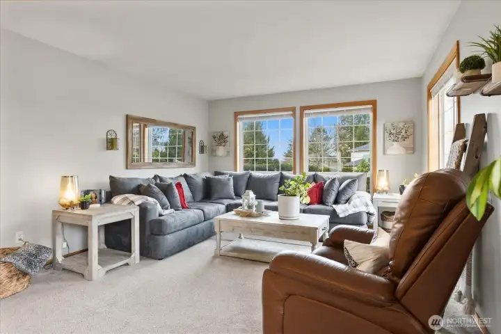 Alternate view of the living room showcasing the sectional seating area and natural light from the large windows.