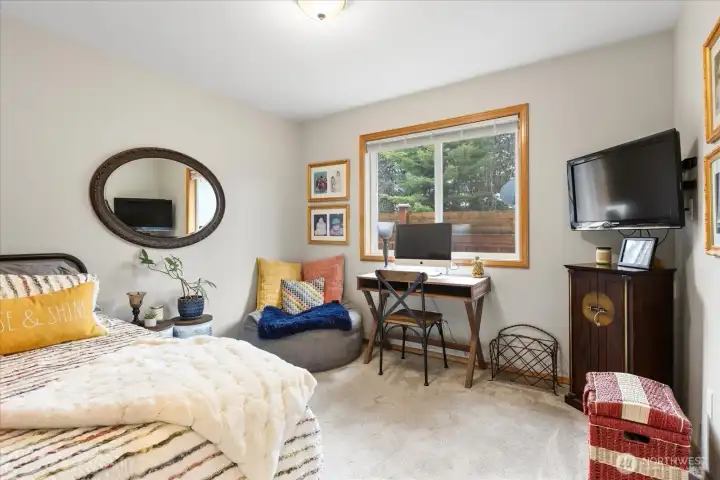 Flexible bedroom with desk area, seating nook, and large window overlooking the yard. Neutral tones support a variety of uses.