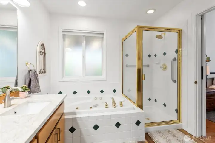 Bathroom with separate jetted tub and enclosed shower. Gold-tone fixtures and tiled surfaces provide a clean, functional layout.