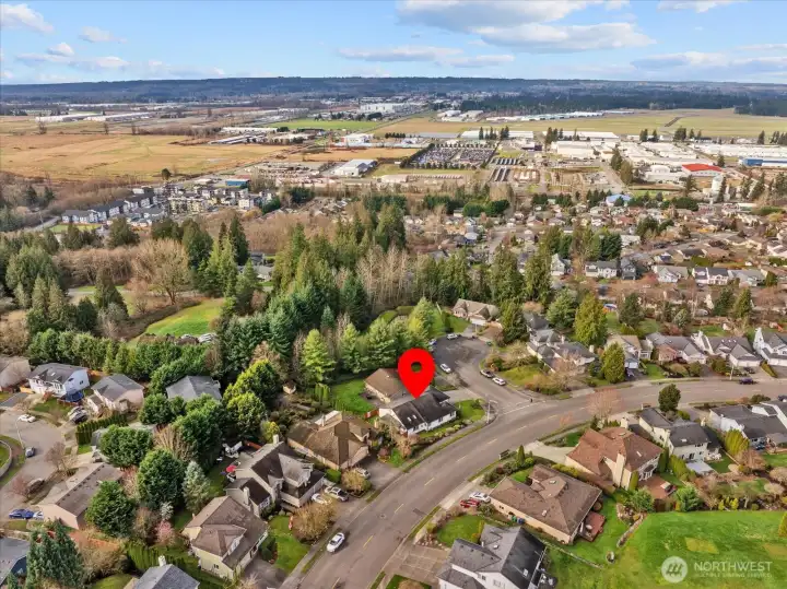 Aerial image showing the home’s location in relation to nearby commercial areas, open land, and surrounding hills.