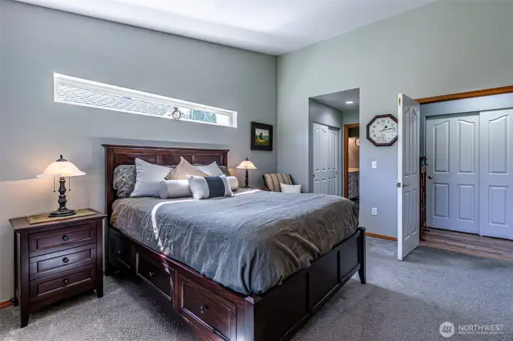 Primary suite with dual closets leading toward en suite bathroom and walk-in closet