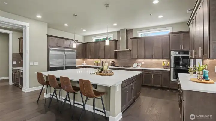 Scene stealing kitchen is a work of art with its enormous island, countless stained ash under-lit cabinets with full extension pullouts, quartz counters and contemporary tile backsplash.