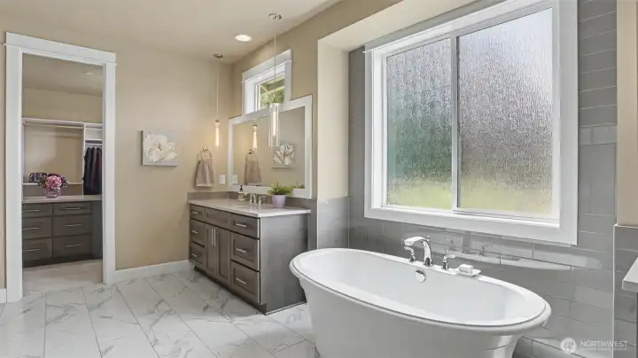 Opulent master bath is a blissful escape with a free standing Maax soaking tub, reeded privacy glass, two separate vanities, quartz counters, and subway tile.