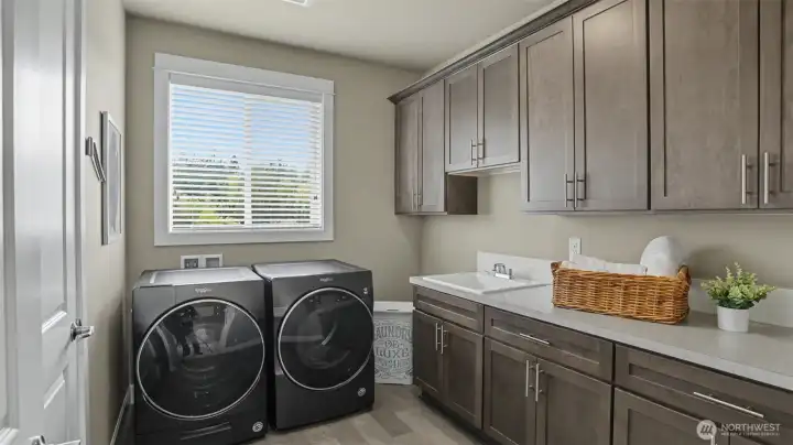 Desirable upper level laundry room offers tons of cabinetry, folding counter, and sink