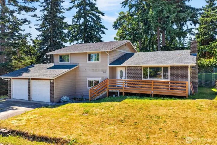 Welcome home to this spacious split-level residence featuring timeless brick accents, a welcoming front deck, a two-car garage, and a peaceful setting surrounded by mature evergreens.
