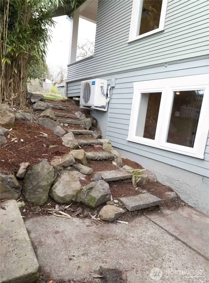 Rustic rock steps lead down to the lower level, adding natural charm and a unique connection between outdoor spaces.