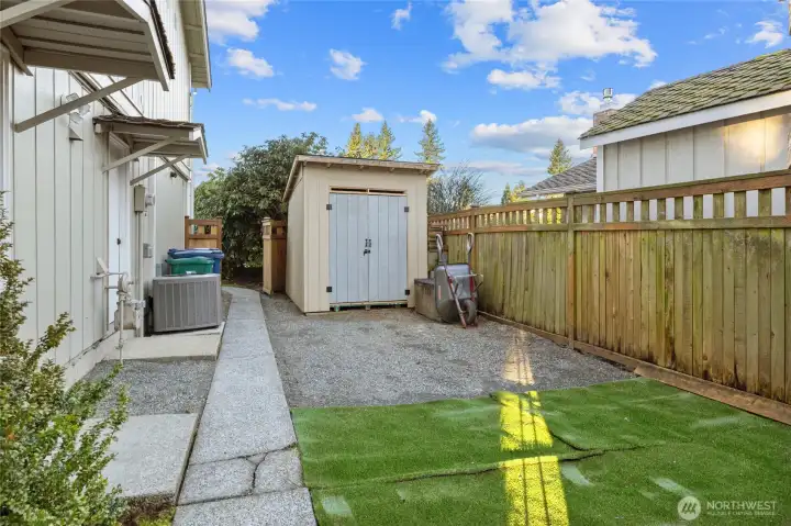 Fenced side yard with shed (that can accommodate a golf card!)  and turf! Great space for pets!
