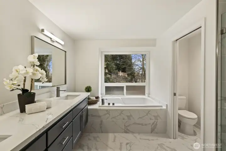 Newly remodeled primary bath includes double vanities, quartz counters, and new tile flooring and shower surround.
