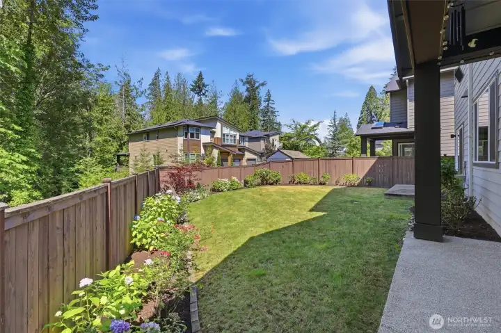 A spacious back yard with plantings all along the fence line. A spacious back yard with plantings all along the fence line.