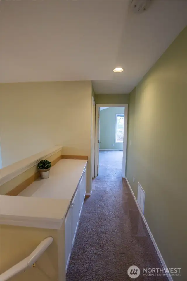 At the top of the stairs is the display and workspace with storage cabinets, leading to the primary ensuite - this is also next to the laundry room and a great place to fold laundry.