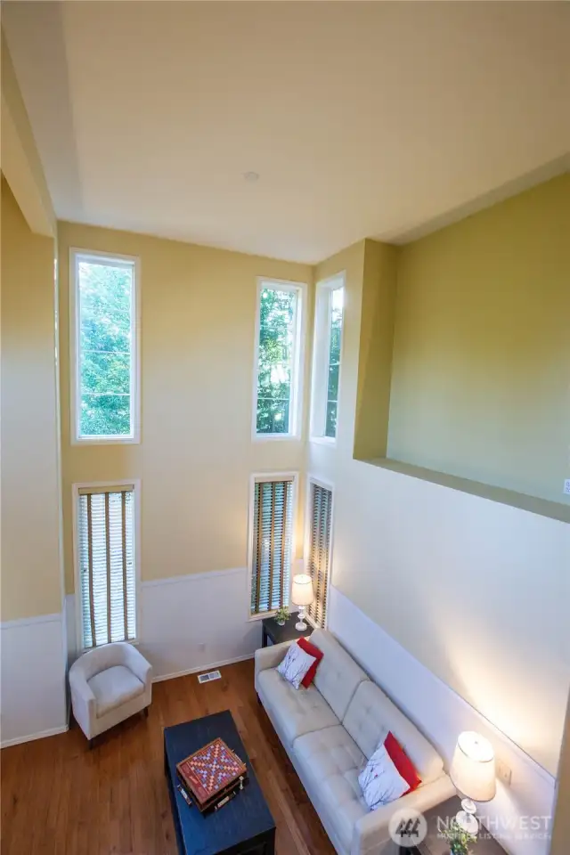 The view looking from the stairs down at the light and open living room area with its wall of windows.