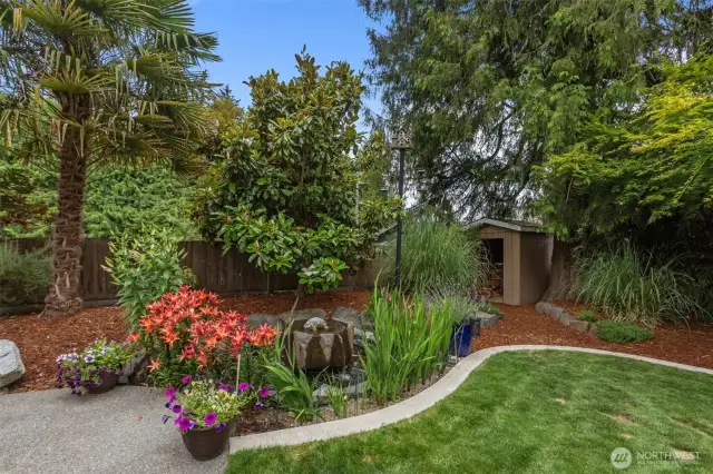 Your private backyard oasis awaits. Enjoy a huge covered patio for entertaining and stunning landscaping with built-in fire pit, water feature, and a ton of lush native and non-native plants! Two generously sized outbuildings provide ample additional storage