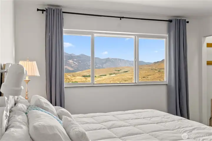 Spacious primary bedroom with large windows framing breathtaking mountain views.