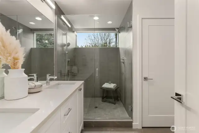 The spa-inspired primary bathroom is a sanctuary of luxury, boasting a double vanity, sleek fixtures, and a spacious glass-enclosed shower.
