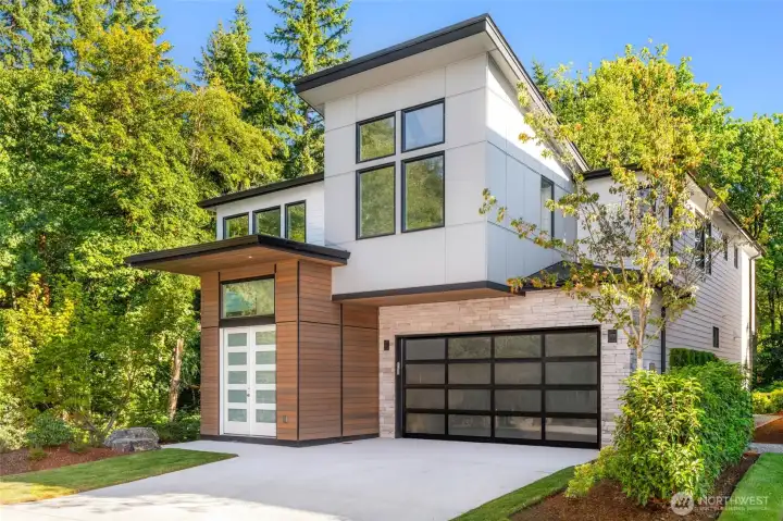 Large stamped concrete driveway, contemporary glass paneled garage door. Cedar surrounded entry with cedar ceiling covered entry