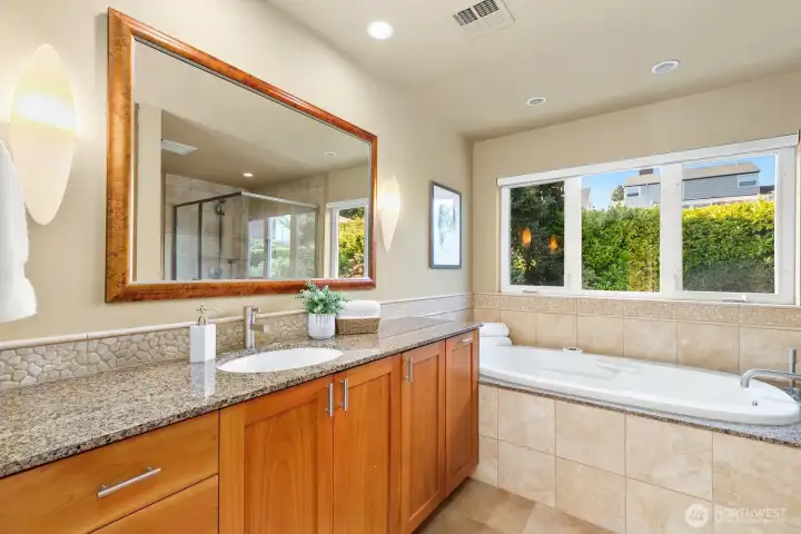 Primary bathroom with granite countertops, jetted tub, and separate shower.