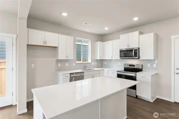 Bright and modern kitchen with full-height backsplash, stainless steel appliances, and ample storage space.  Pictures are for representational purposes only, colors and features may vary.
