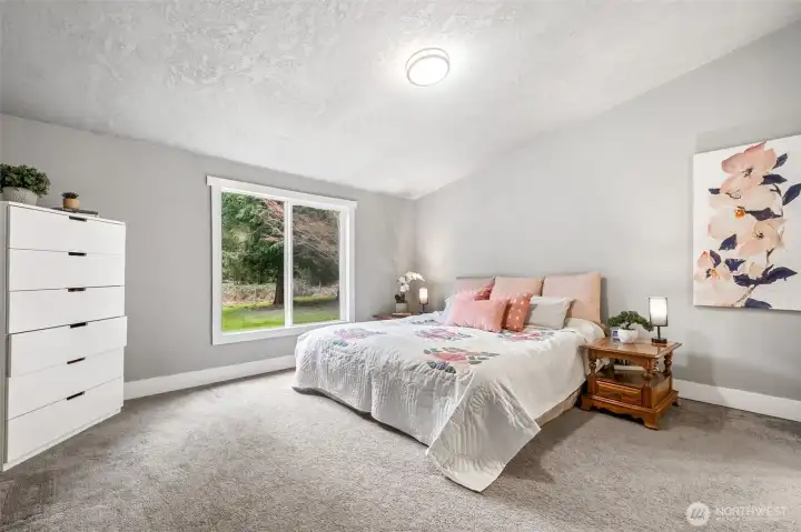 The primary bedroom offers a peaceful retreat with soft natural tones and ample space for rest and relaxation. The vaulted ceilings further add to the spaciousness of the room. It’s a room designed for comfort.