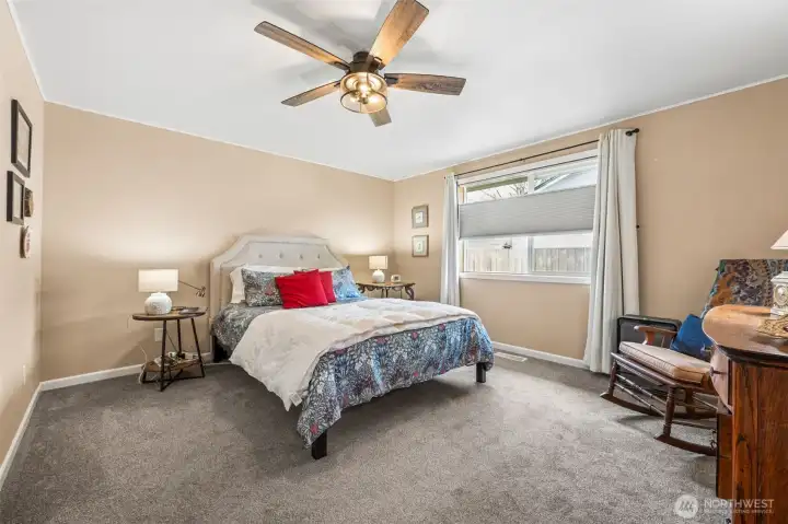 There is something instantly relaxing about this primary bedroom. The soft mushroom toned carpet and warm latte walls create a neutral backdrop that works with just about any décor direction. A ceiling fan adds everyday comfort, and the adjustable top down, bottom up blinds are a standout feature, letting sunlight pour in from above while the lower half stays private. With a king bed already in place and still generous breathing room around it, the layout easily supports extra seating, a dresser wall, or that one indulgent lounge chair you have been wanting.